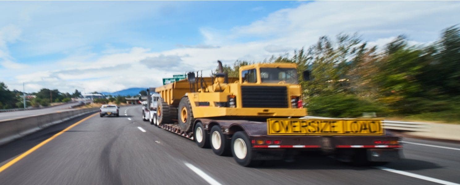 A large truck with Oversized Load banner on the back